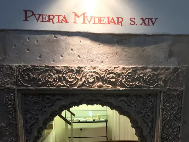 Arco decorado en piedra con inscripción histórica en pared.