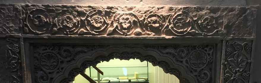 Arco decorado en piedra con inscripción histórica en pared.