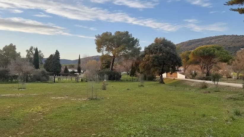 Pradera ajardinada con árboles y sendero junto a una loma