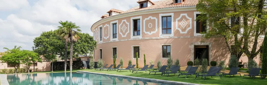 Fachada curva con piscina rectangular y tumbonas sobre césped.