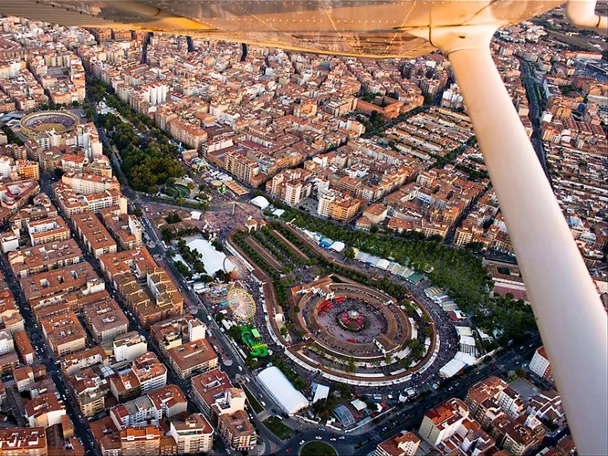 Vista aérea nocturna de un recinto ferial con iluminación intensa y multitud concentrada en el centro.