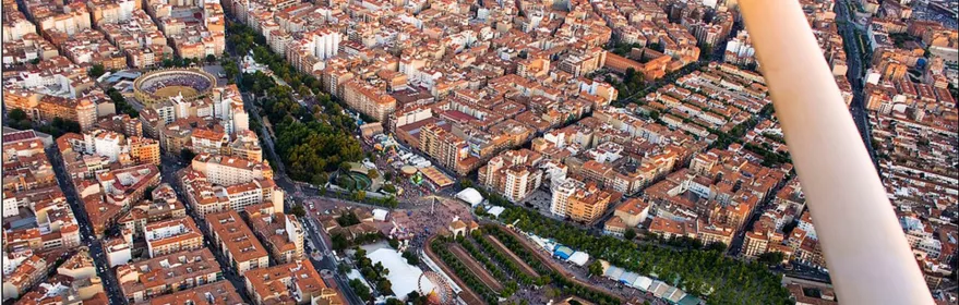 Vista aérea nocturna de un recinto ferial con iluminación intensa y multitud concentrada en el centro.