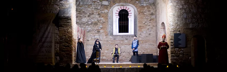 Representación teatral nocturna en escenario de piedra iluminado.