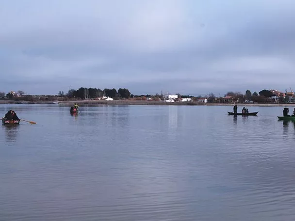 Personas pescando desde pequeñas barcas en una laguna tranquila.