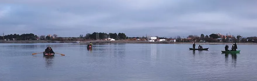 Personas pescando desde pequeñas barcas en una laguna tranquila.