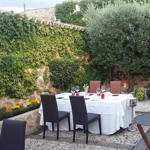 Terraza interior con mesas vestidas y muros cubiertos de hiedra.
