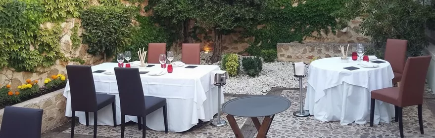 Terraza interior con mesas vestidas y muros cubiertos de hiedra.