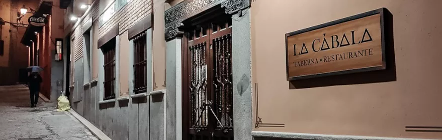 Fachada de restaurante en calle empedrada de noche con cartel iluminado.