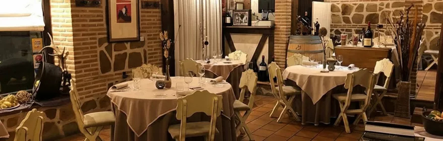 Restaurante tradicional con vigas de madera, paredes de piedra y mesas preparadas.