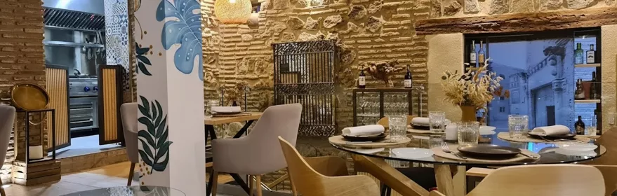 Comedor con mesa redonda, sillones tapizados y cocina vista al fondo.