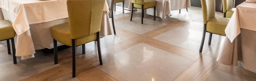 Comedor luminoso con mesas vestidas, sillas tapizadas y grandes ventanales con estores.