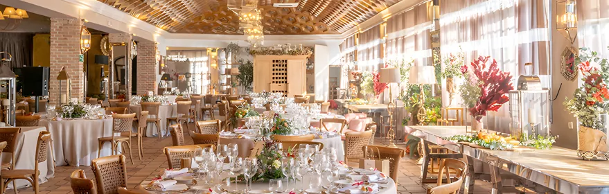 Salón elegante con mesas preparadas y grandes ventanales luminosos