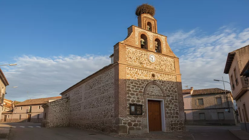 Una plaza adoquinada con jardineras de madera, bancos de piedra y una fuente central ornamentada, rodeada de edificios de apartamentos residenciales.