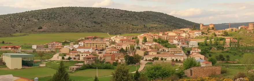 Vista panorámica de un pueblo entre colinas y campos verdes
