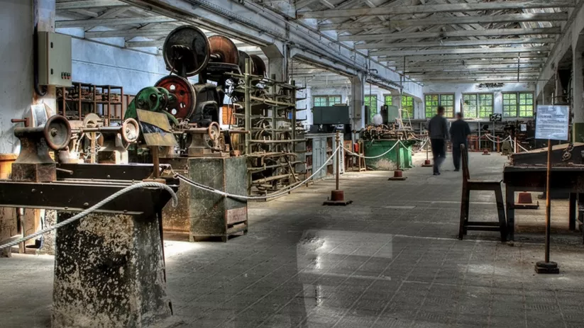 Sala amplia con maquinaria antigua y visitantes recorriendo el espacio.
