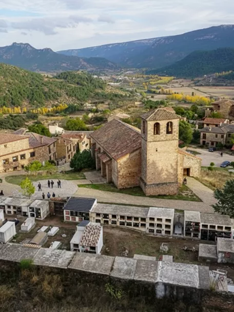 Vista aérea de conjunto rural con iglesia y montañas al fondo.