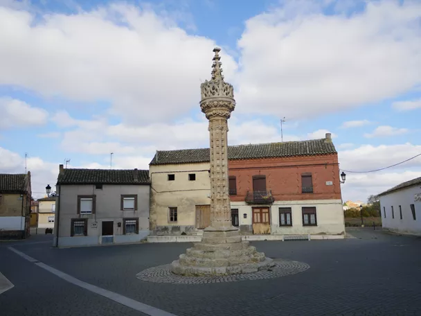 Columna monumental de piedra en una plaza con casas bajas