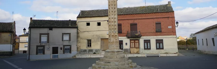 Columna monumental de piedra en una plaza con casas bajas