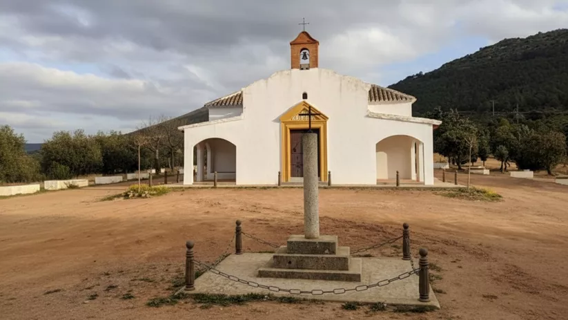 Ermita blanca vista frontal con cruz de piedra delante