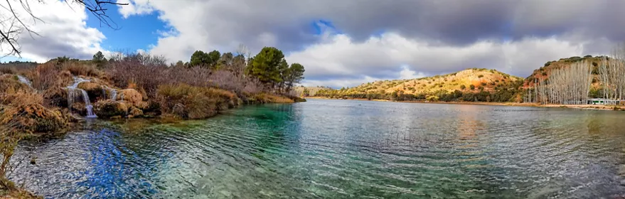 Laguna de agua clara rodeada de vegetación y colinas.