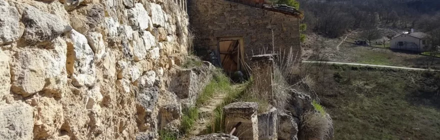 Sendero junto a muro de piedra en ladera rocosa.