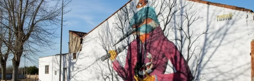 Mural de ave antropomórfica pintado en fachada blanca junto a valla de madera.