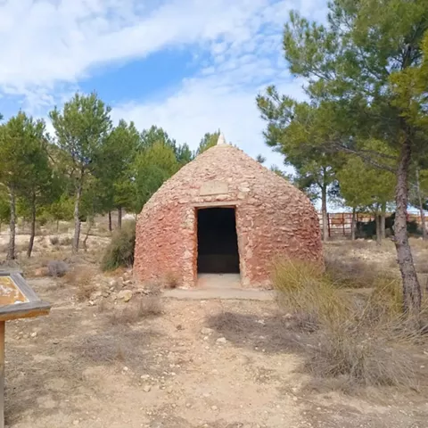 Chozo de piedra rojiza en un paraje natural