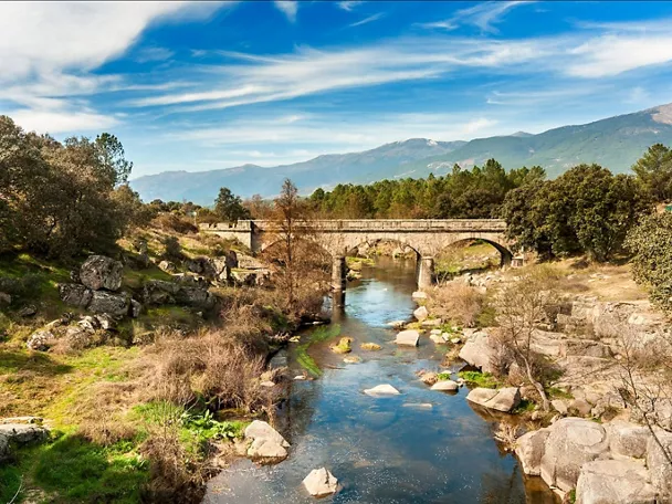 Puente de piedra sobre un río entre rocas y montañas