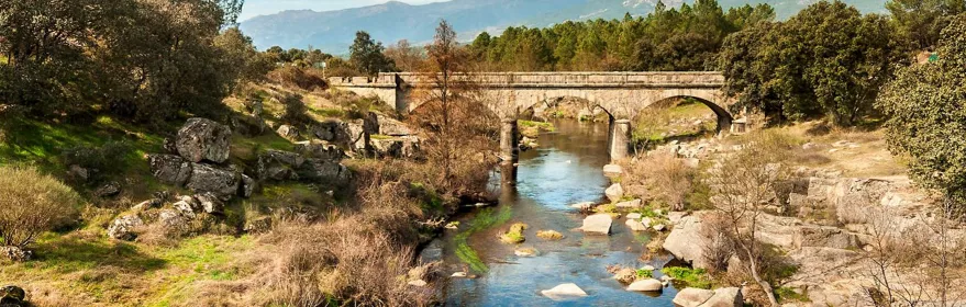 Puente de piedra sobre un río entre rocas y montañas