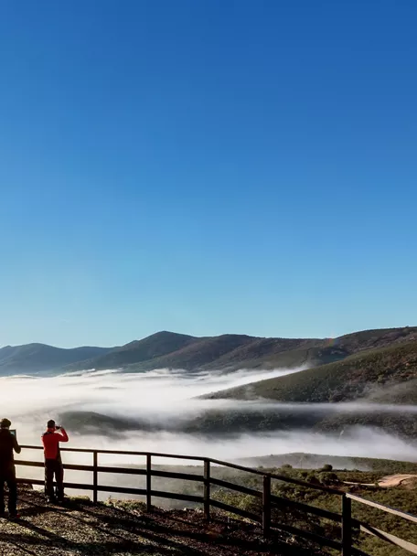 Mirador con personas observando mar de nubes.