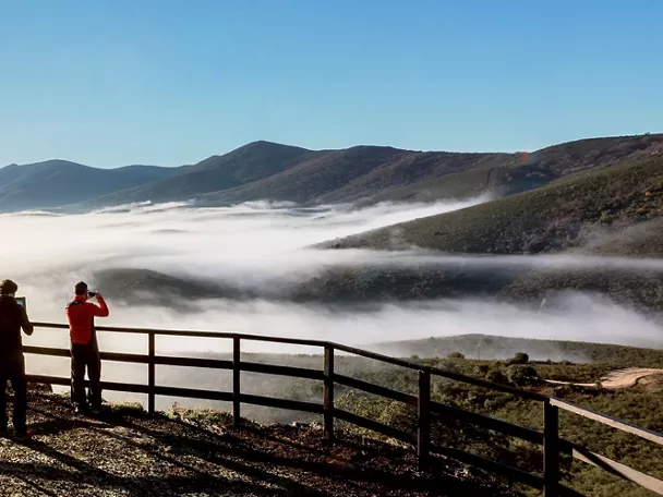 Mirador con personas observando mar de nubes.