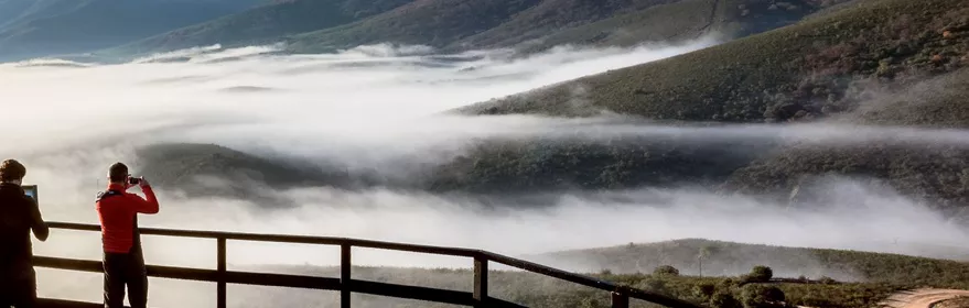 Mirador con personas observando mar de nubes.