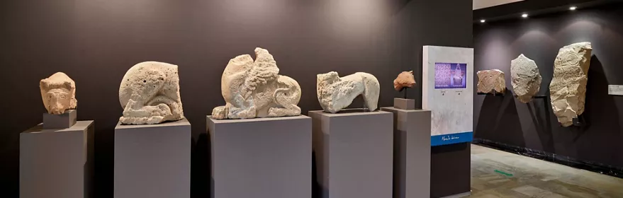 fragmentos escultóricos de piedra expuestos sobre pedestales en sala museística