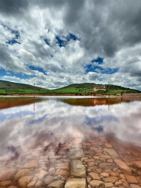 Lámina de agua rojiza bajo cielo nuboso