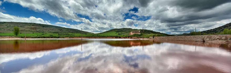 Lámina de agua rojiza bajo cielo nuboso