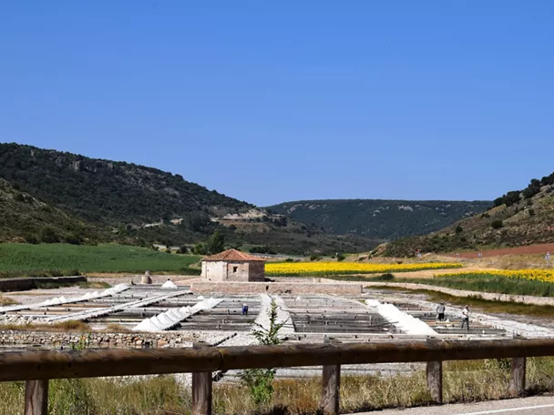 Antiguas balsas de evaporación con edificio de piedra en un valle agrícola.