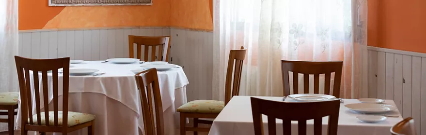 Salón acogedor con paredes naranjas y mesas vestidas de blanco