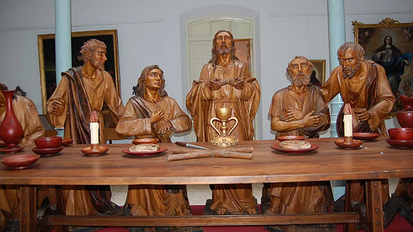Detalle de figuras talladas en madera sentadas a una mesa ceremonial
