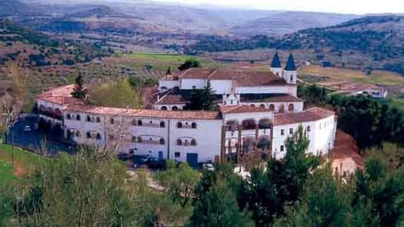 Vista aérea de conjunto arquitectónico blanco entre vegetación y paisaje rural.