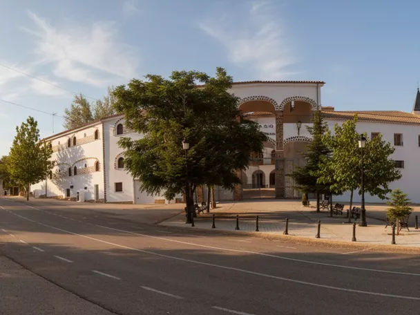 Vista panorámica de un gran edificio blanco junto a una carretera arbolada.