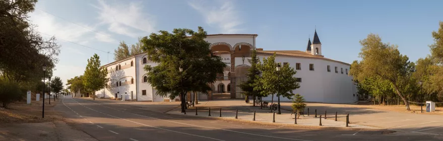 Vista panorámica de un gran edificio blanco junto a una carretera arbolada.