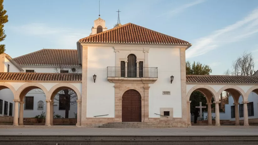 Fachada blanca con pórticos de arcos y balcón central en una plaza amplia.