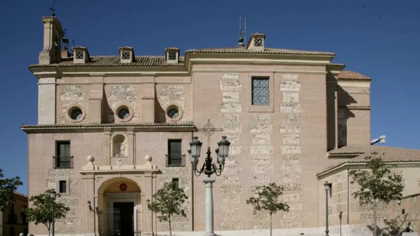 Fachada de edificio histórico de ladrillo y piedra en plaza abierta.