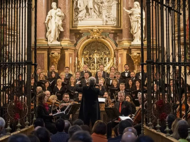 Coro y orquesta interpretando música sacra tras reja de capilla