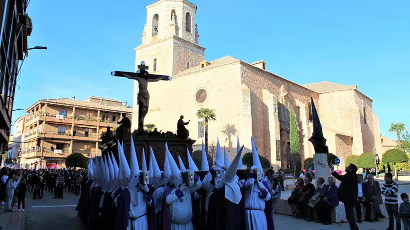 Paso religioso con crucificado frente a iglesia histórica