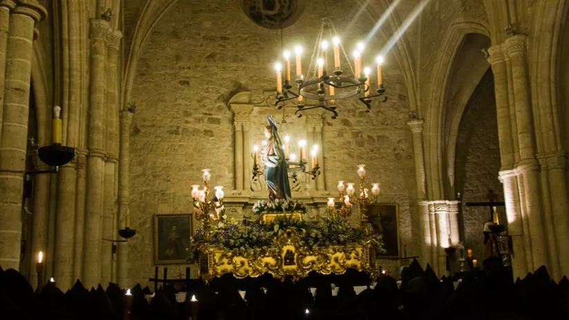 Paso religioso iluminado en el interior de un templo durante una procesión