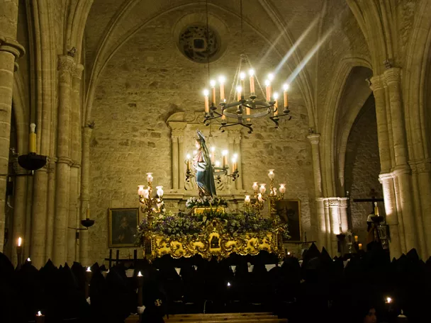 Paso religioso iluminado en el interior de un templo durante una procesión