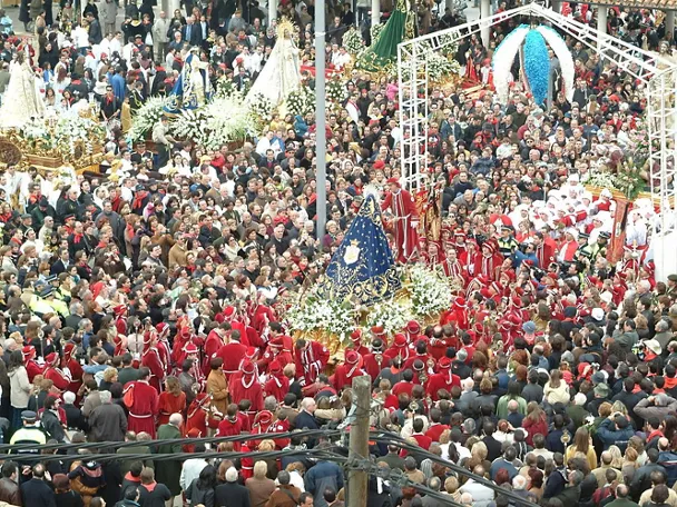 Gran concentración de personas alrededor de varios pasos procesionales en un espacio urbano.