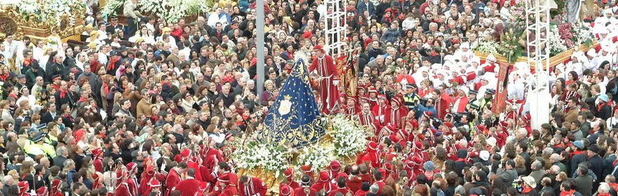 Gran concentración de personas alrededor de varios pasos procesionales en un espacio urbano.
