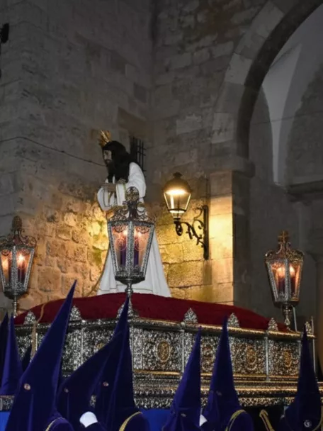 Paso religioso nocturno con nazarenos de túnica azul.
